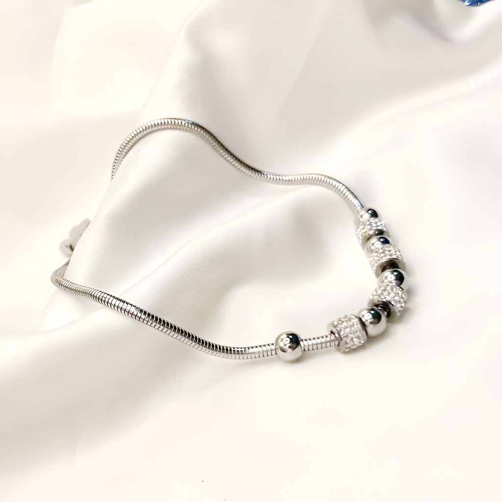 Bracelet en titane argenté avec perles et pierres de cristal brillantes, design élégant et raffiné.