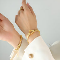 Bracelet en titane plaqué or avec maille élégante et motif cœur doré porté au poignet féminin.