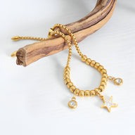 Bracelet en titane plaqué or à perles rondes et médaillon étoile serti de pierres blanches.