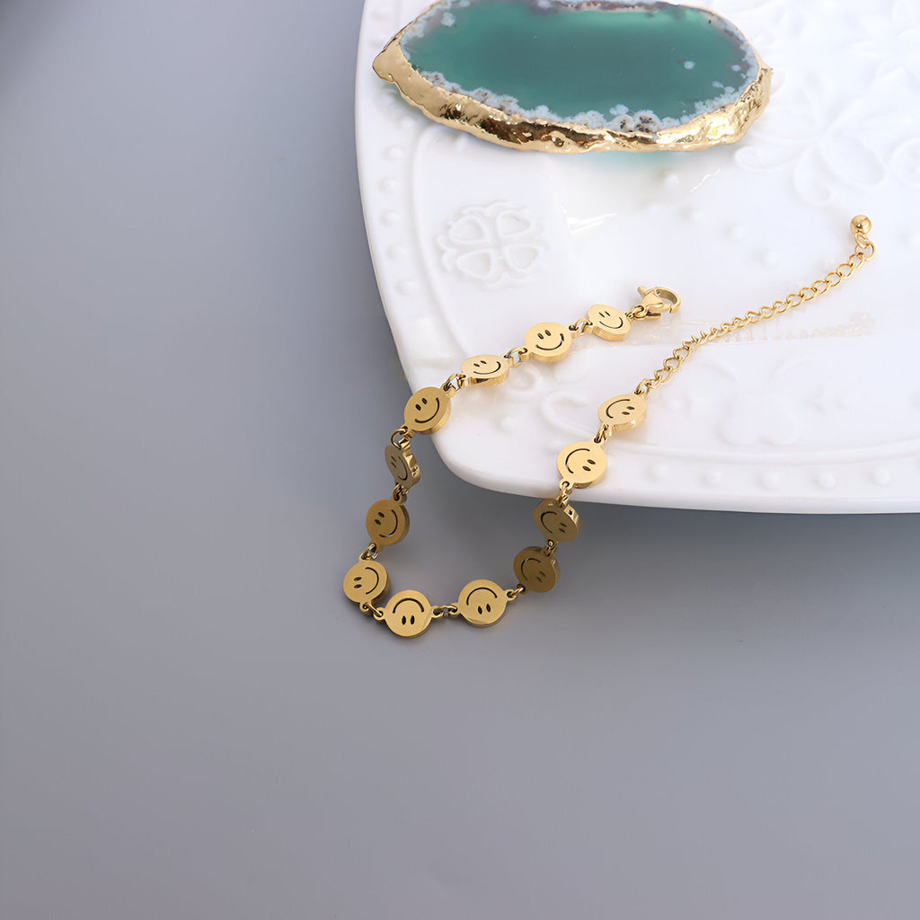 Bracelet en titane plaqué or avec motifs smileys ronds et chaîne de réglage élégante.