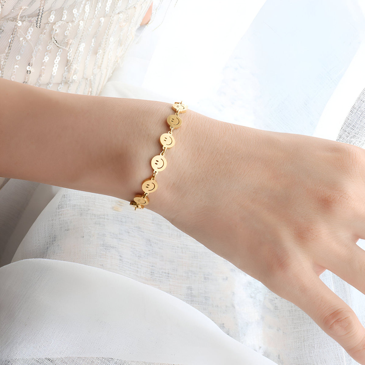 Bracelet fin en titane plaqué or avec motifs smileys alignés sur poignet féminin.