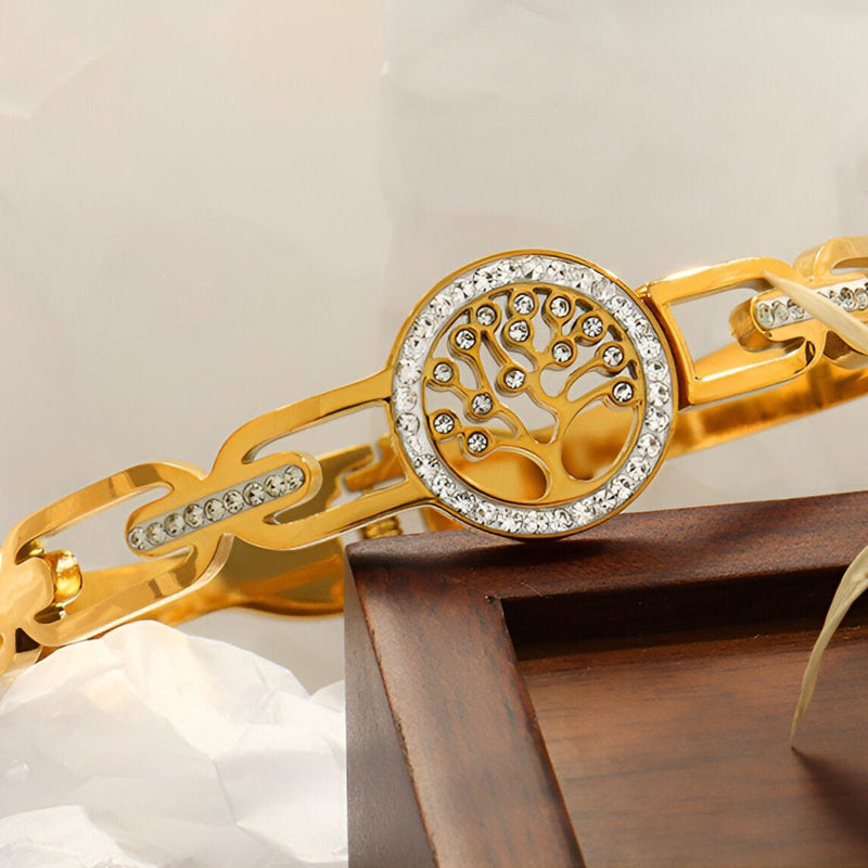 Bracelet en titane doré pour femme avec pendentif arbre de vie orné de petits cristaux blancs.