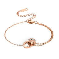Bracelet en titane or rosé avec duo de cercles entrelacés, chiffres romains gravés, design élégant féminin.
