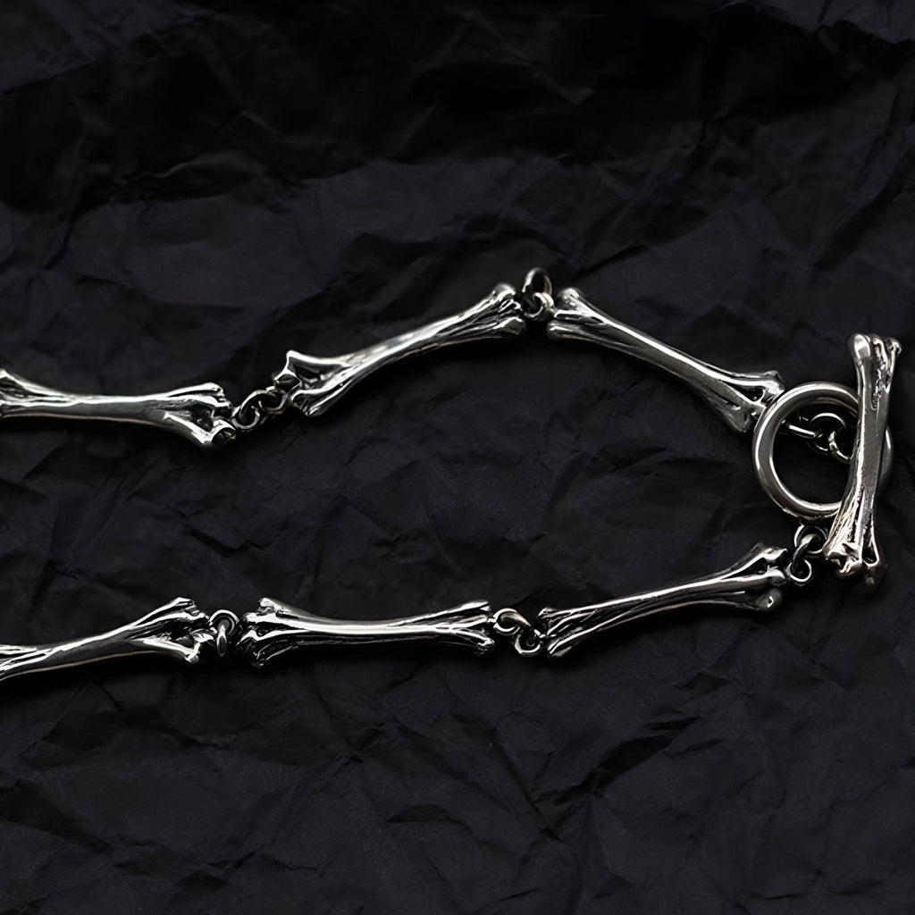 Bracelet en titane argenté avec maillons en forme d'os et fermoir anneau rond.
