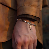 Bracelet en titane argenté style ossement avec croix chrétienne fine pendante, porté au poignet homme.