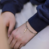 Bracelet en titane argenté avec maillons ossement et pendentif croix chrétienne porté au poignet homme.