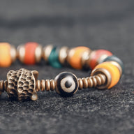 Bracelet en cuivre avec perles en verre multicolore, style ethnique, détail texturé sur une perle bronze.