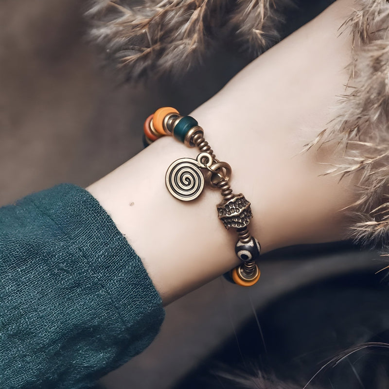 Bracelet en cuivre avec perles en verre coloré et pendentif spirale, style bohème élégant.