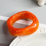 Bracelet épais en acrylique orange marbré avec forme géométrique élégante.