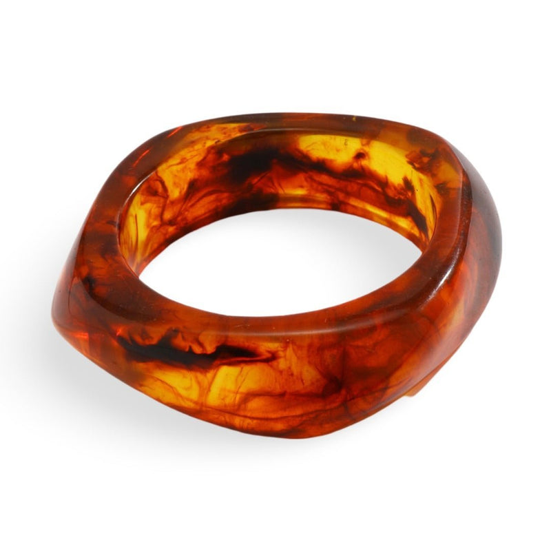 Bracelet épais en acrylique marron effet écaille avec forme légèrement ondulée.