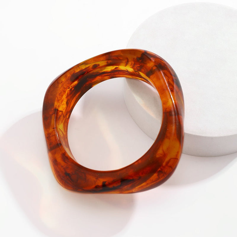 Bracelet épais en acrylique marron avec effet écaille de tortue et forme carrée arrondie.