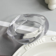 Bracelet épais en acrylique transparent avec finition lisse et forme incurvée élégante.
