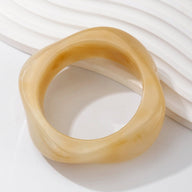 Bracelet épais en acrylique beige marbré avec forme organique irrégulière.