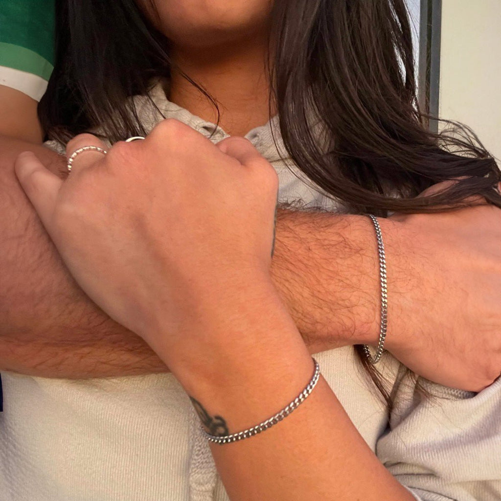 Bracelet en acier inoxydable argenté à maillons fins porté au poignet, style unisexe et épuré.