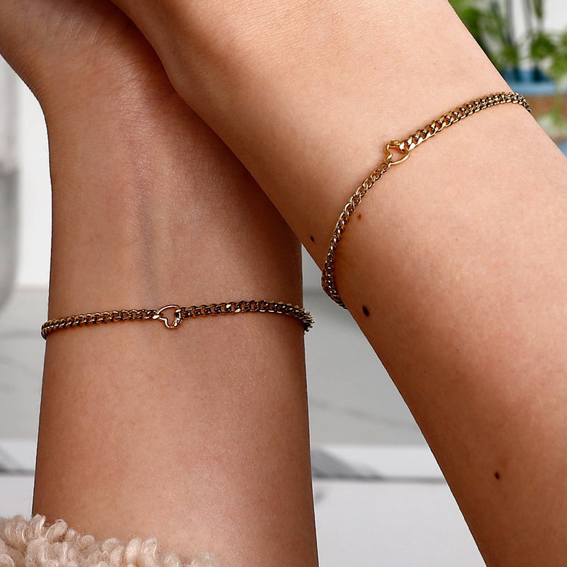 Bracelet fin en acier inoxydable doré avec un petit cadenas en forme de cœur au centre.