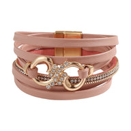 Bracelet femme multi-rangs rose poudré en simili cuir avec strass, fermoir magnétique doré, motif infini orné de cristaux.
