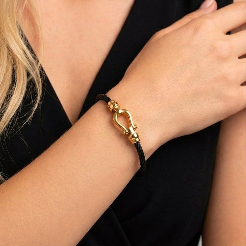 Bracelet jonc noir en câble torsadé avec fer à cheval et fermoir doré élégant pour femme.