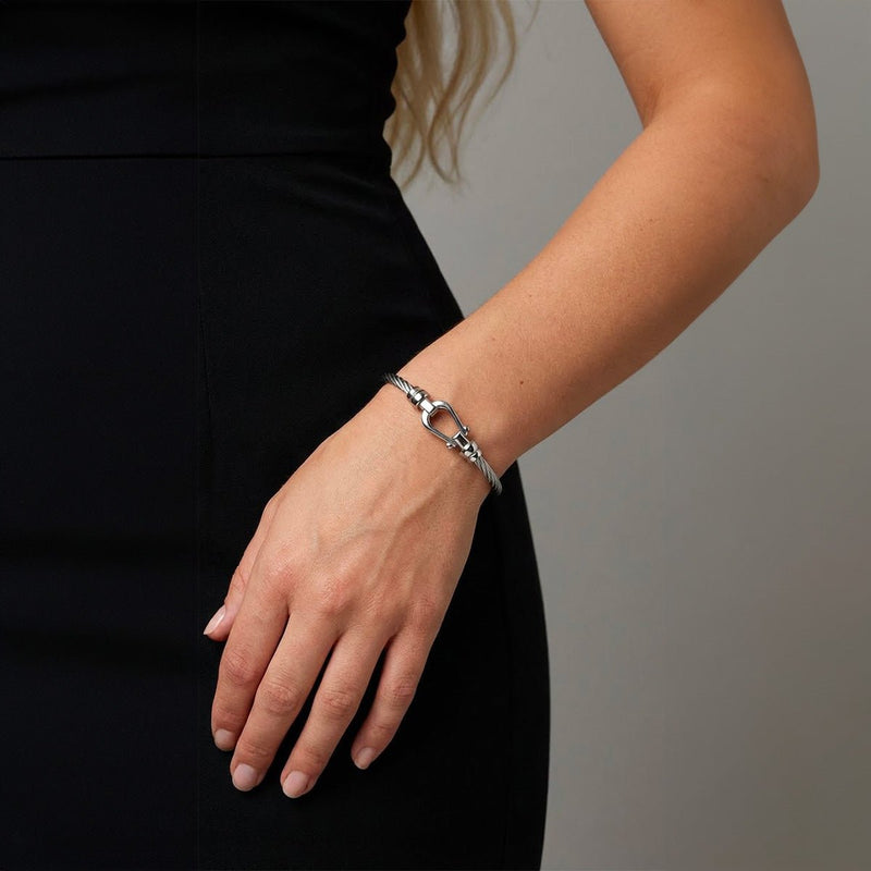 Bracelet jonc fer à cheval en acier inoxydable câble torsadé, finition argentée élégante sur poignet féminin.