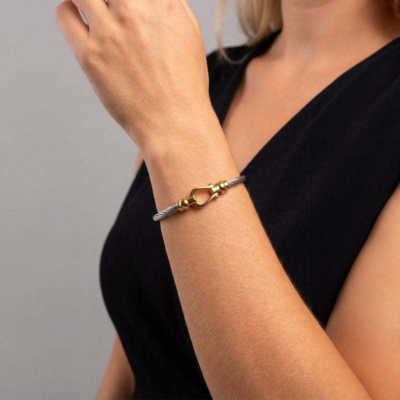 Bracelet jonc en acier inoxydable torsadé avec détail fer à cheval doré, style élégant et féminin.