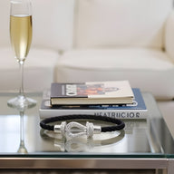 Bracelet fer à cheval en titane noir avec fermoir argenté, style Annabelle, posé sur table en verre.