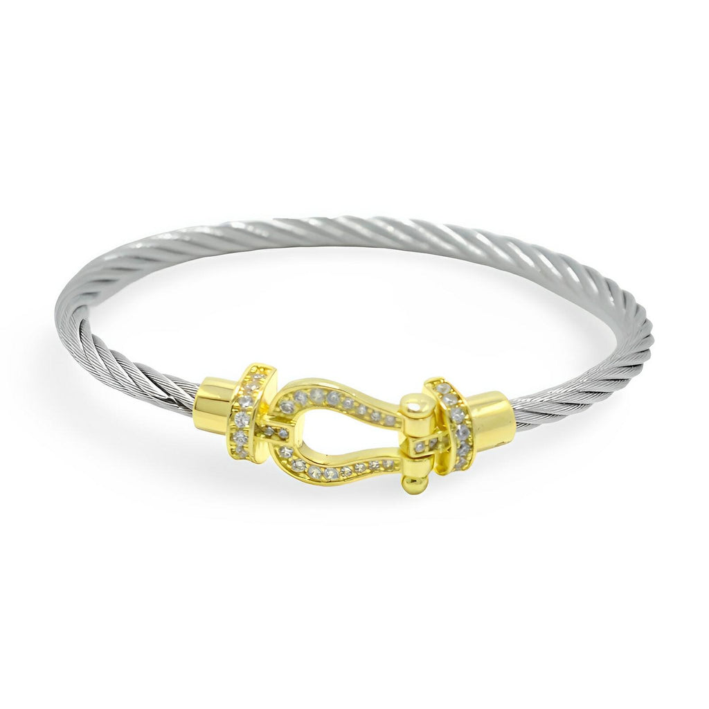 Bracelet fer à cheval en cordon titane argenté avec fermoir doré orné de cristaux blancs.