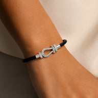 Bracelet femme cordon noir en titane avec fermoir fer à cheval argent serti de pierres brillantes.