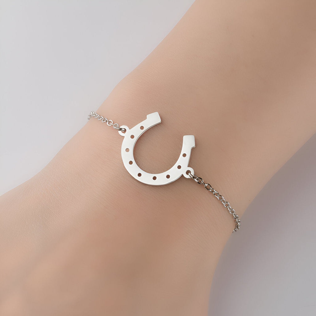 Bracelet femme en acier inoxydable argenté avec pendentif fer à cheval ajouré.