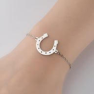 Bracelet femme en acier inoxydable argenté avec pendentif fer à cheval ajouré.