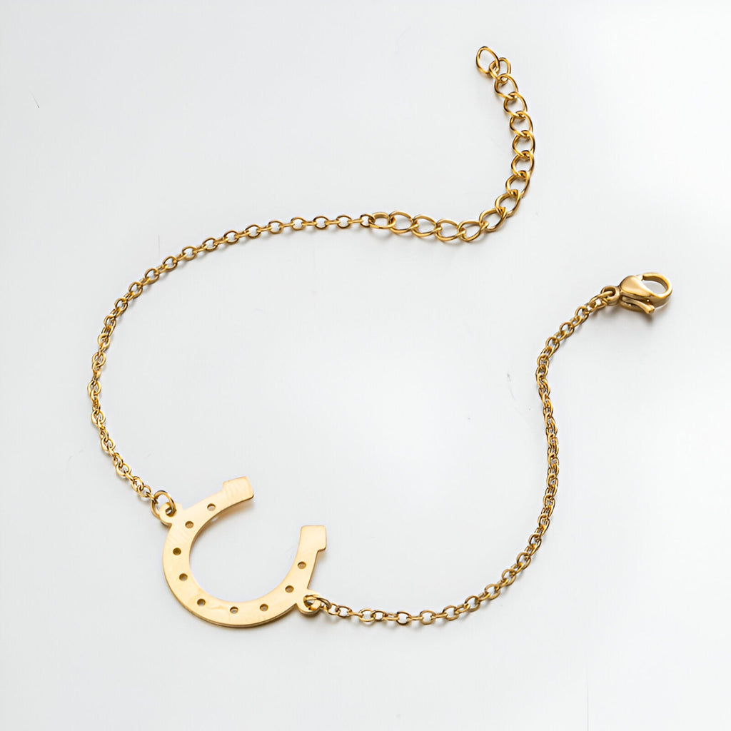 Bracelet fin en acier inoxydable doré avec pendentif fer à cheval ajouré et chaîne ajustable.