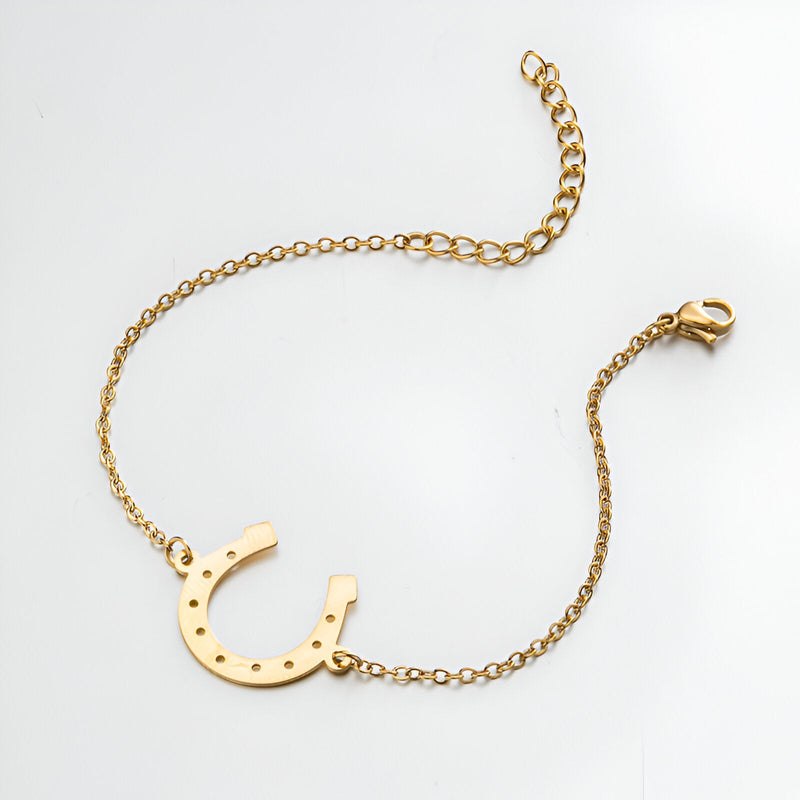 Bracelet fin en acier inoxydable doré avec pendentif fer à cheval ajouré et chaîne ajustable.