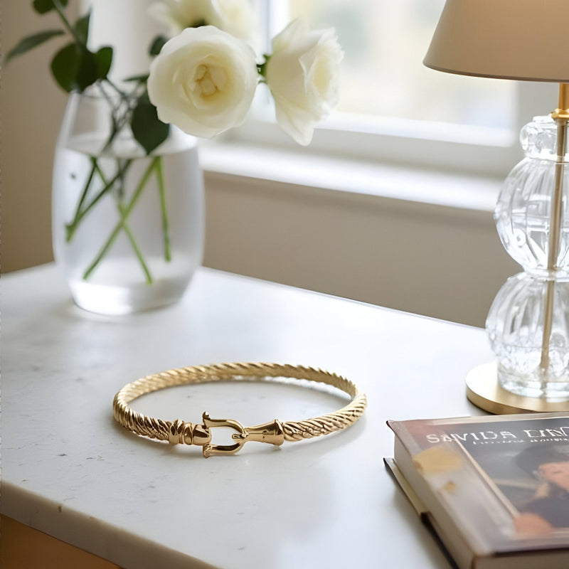 Bracelet fer à cheval en acier inoxydable doré, tressé avec fermoir en forme de fer à cheval.