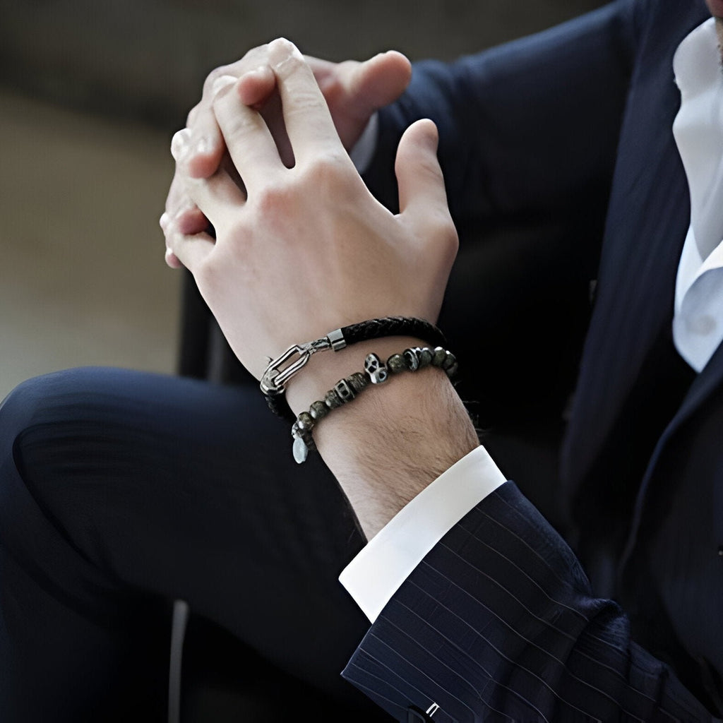 Bracelet fer à cheval en cuir noir avec détails en acier inoxydable argenté porté sur poignet masculin.