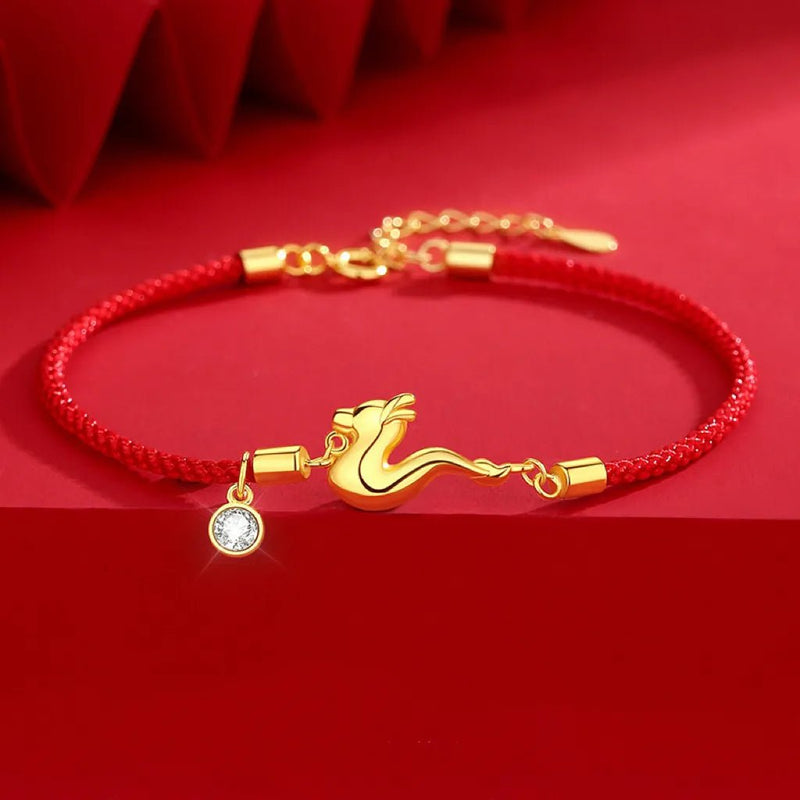 Bracelet fil rouge tressé avec breloque dorée souffle de dragon et pendentif strass blanc.