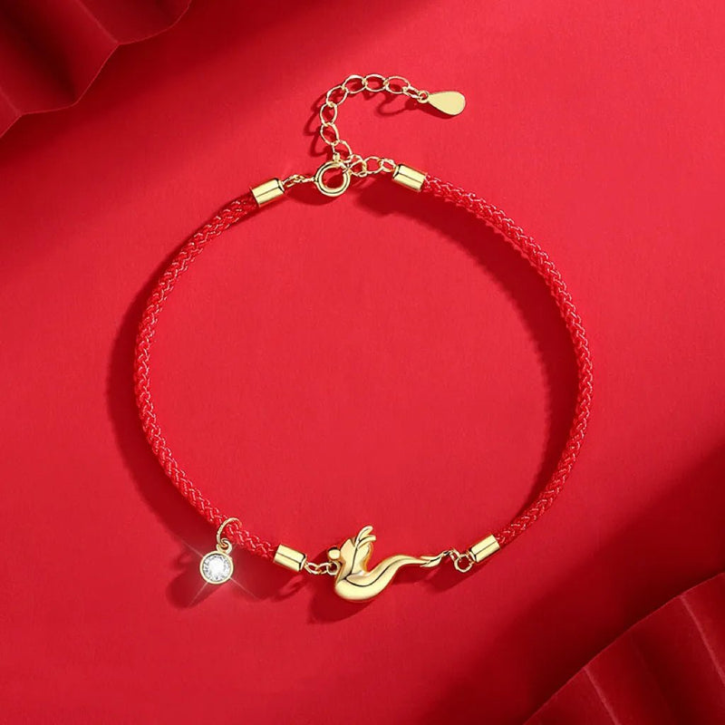 Bracelet rouge en fil tressé avec pendentif oiseau doré et breloque strassée ajustable.