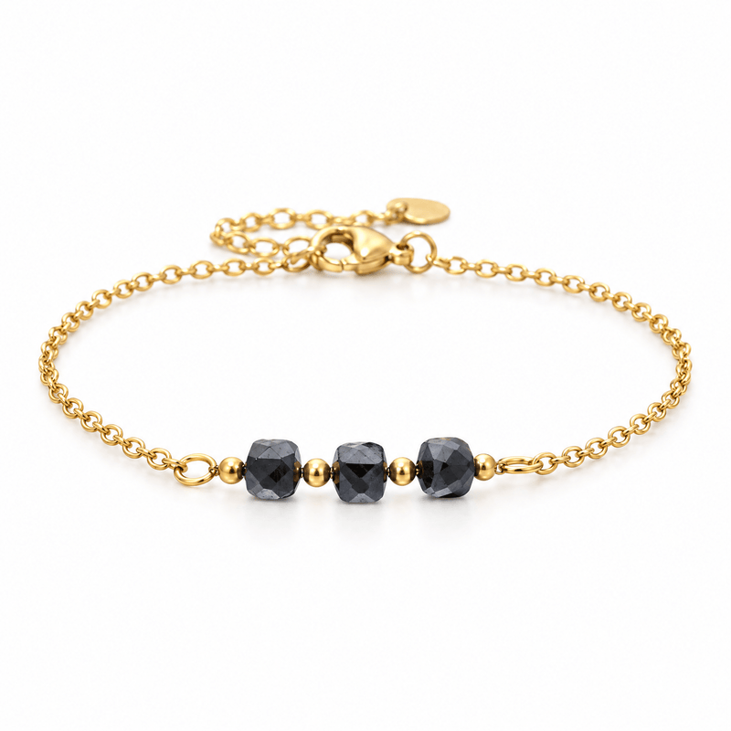 Packshot studio bracelet Bracelet fin en acier doré, maille forçat, trois pierres naturelles facettées, bijou élégant et lumineux, modèle Ilumia — Hématite, vue frontale basse, fond blanc pur, détails verrouillés