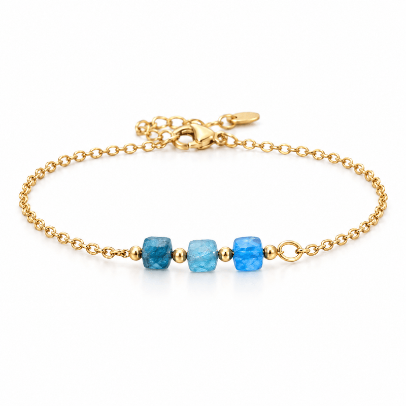 Packshot studio bracelet Bracelet fin en acier doré, maille forçat, trois pierres naturelles facettées, bijou élégant et lumineux, modèle Ilumia — Apatite bleu, vue frontale basse, fond blanc pur, détails verrouillés