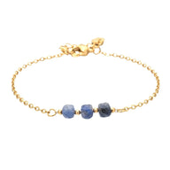 Bracelet fin en acier doré avec trois pierres semi-précieuses bleu facettées sur maille forçat délicate.