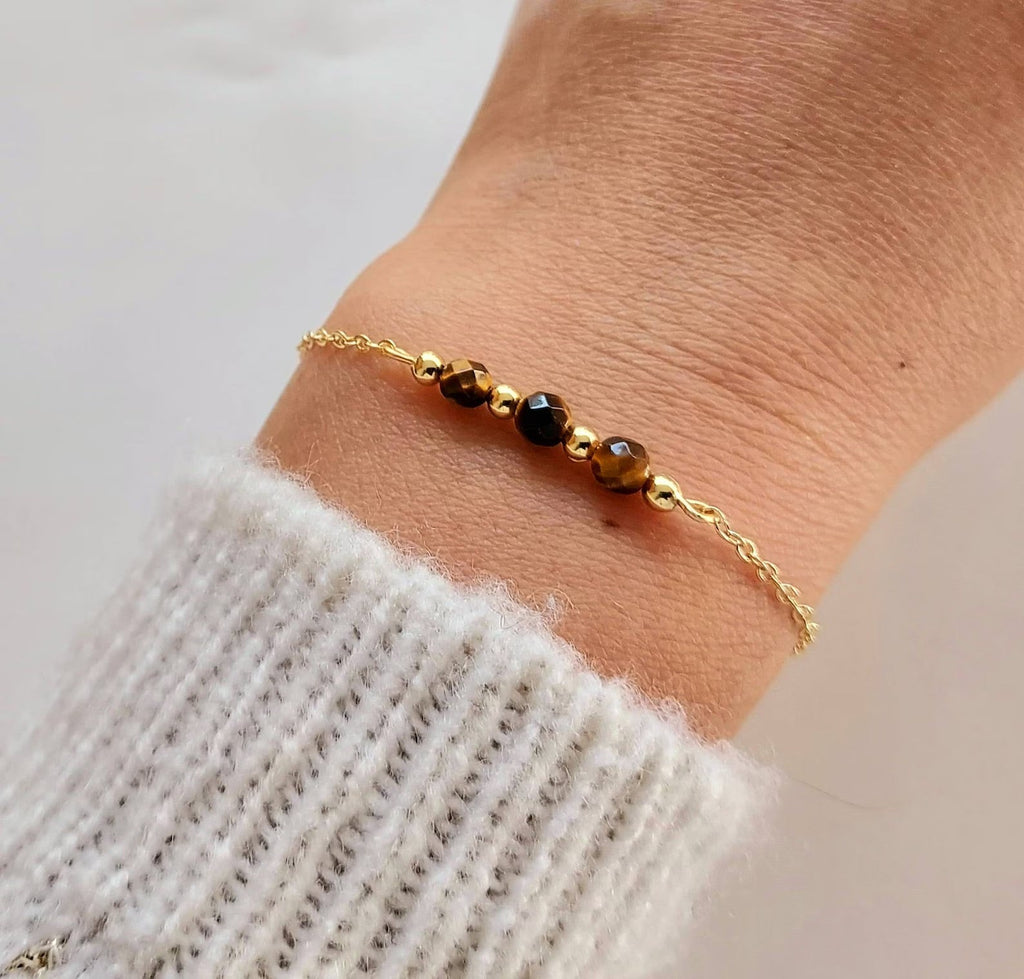 Bracelet fin en acier doré avec maille forçat et trois pierres semi-précieuses facettées noires et dorées.