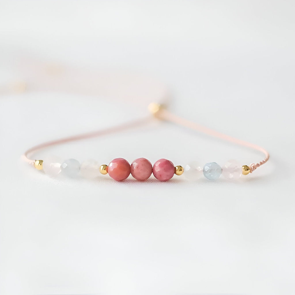 Bracelet fin en pierres naturelles rose et bleu clair avec perles dorées sur fil délicat rose pâle.