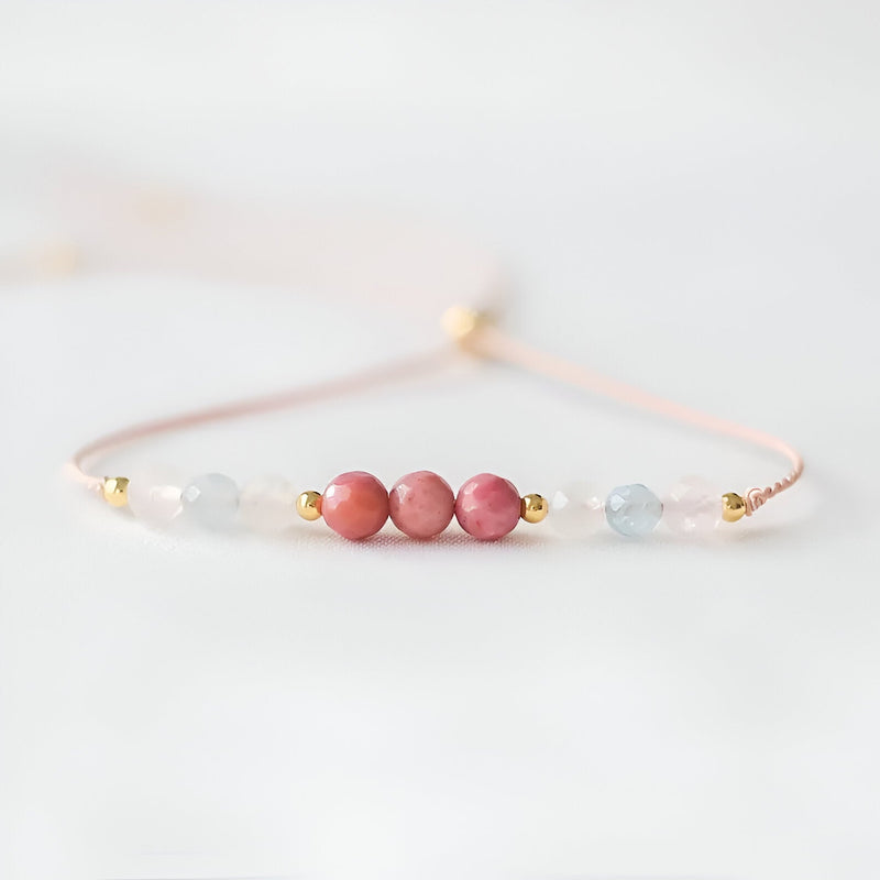 Bracelet fin en pierres naturelles rose et bleu clair avec perles dorées sur fil délicat rose pâle.