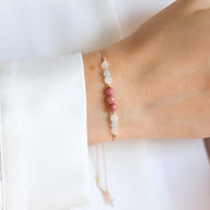 Bracelet fin en pierres naturelles rose et blanches sur poignet, style délicat et élégant.