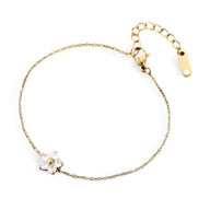 Bracelet fin en acier inoxydable avec petite fleur blanche et détail doré, chaîne délicate réglable.