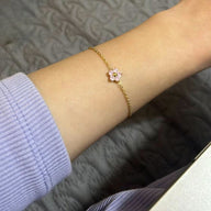 Bracelet en acier inoxydable doré avec petite fleur rose au centre, chaîne fine délicate.