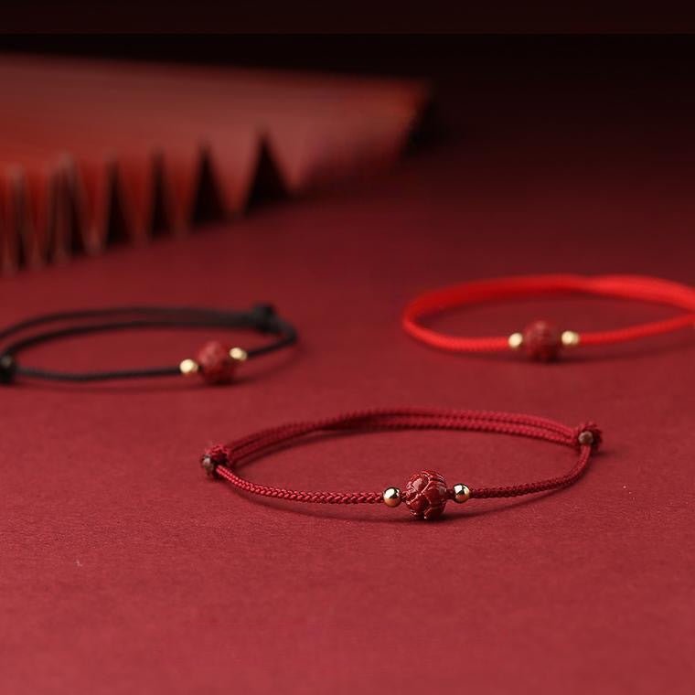 Trois bracelets fins en coton rouge, bordeaux et noir avec motif fleur de lotus cinabre et perles dorées.