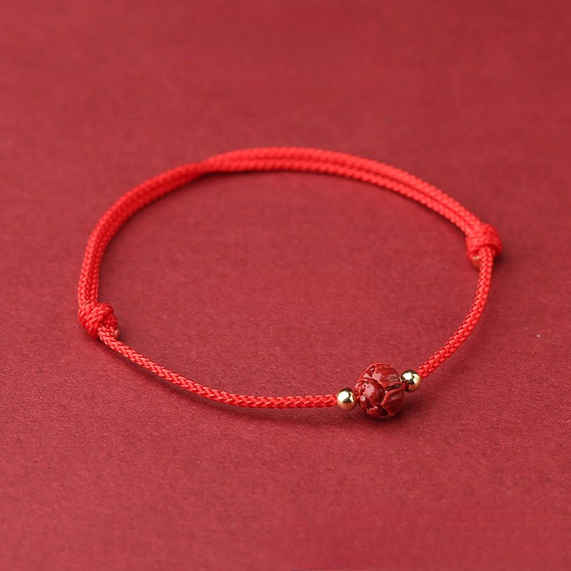 Bracelet en coton fil rouge avec perle fleur de lotus cinabre et petits détails dorés.