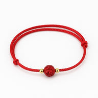 Bracelet rouge en coton fil rouge avec perle sculptée fleur de lotus et petites perles dorées.