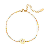 Bracelet fin en or avec chaîne colorée et médaille ronde gravée d'un flocon de neige.