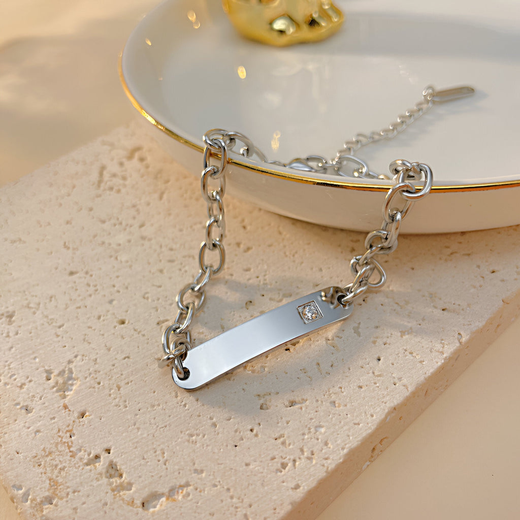 Bracelet gourmette argent en acier inoxydable avec pierre de zirconium sur plaque lisse et chaîne épaisse.