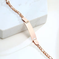 Bracelet gourmette en acier inoxydable or rosé avec maille figaro et plaque personnalisable.