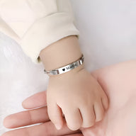 Bracelet gourmette personnalisé en acier inoxydable argent avec maille figaro sur poignet d'enfant.